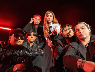 A dramatic promotional photo of Filipino pop-rock band NOBITA with Yeng Constantino, all dressed in dark, stylish outfits against a black-and-red backdrop. The group poses with serious, intense expressions, exuding a moody and powerful vibe that matches the emotional tone of their new single “Gayuma”.