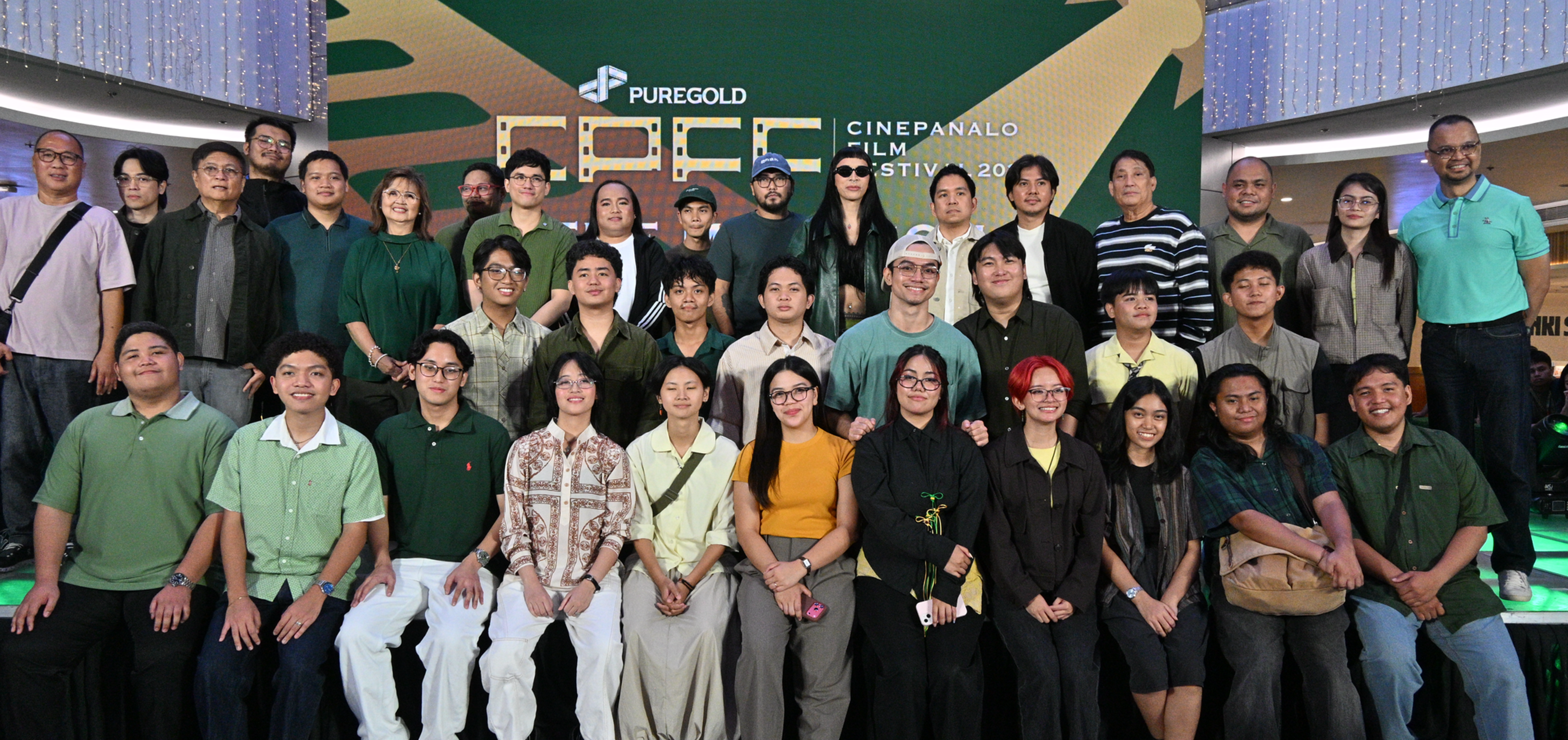 Group portrait of smiling people at Puregold CinePanalo Film Festival 2026 in a mall atrium, with a green backdrop and lights.