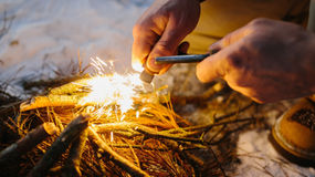 A close-up of a man starting a fire