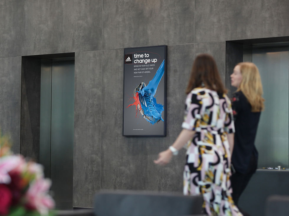 Two ladies walking past an elevator DOOH screen
