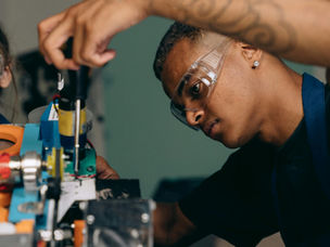 Two young technicians focus on electronic equipment assembly in a workshop setting