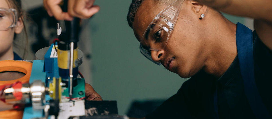 Two young technicians focus on electronic equipment assembly in a workshop setting