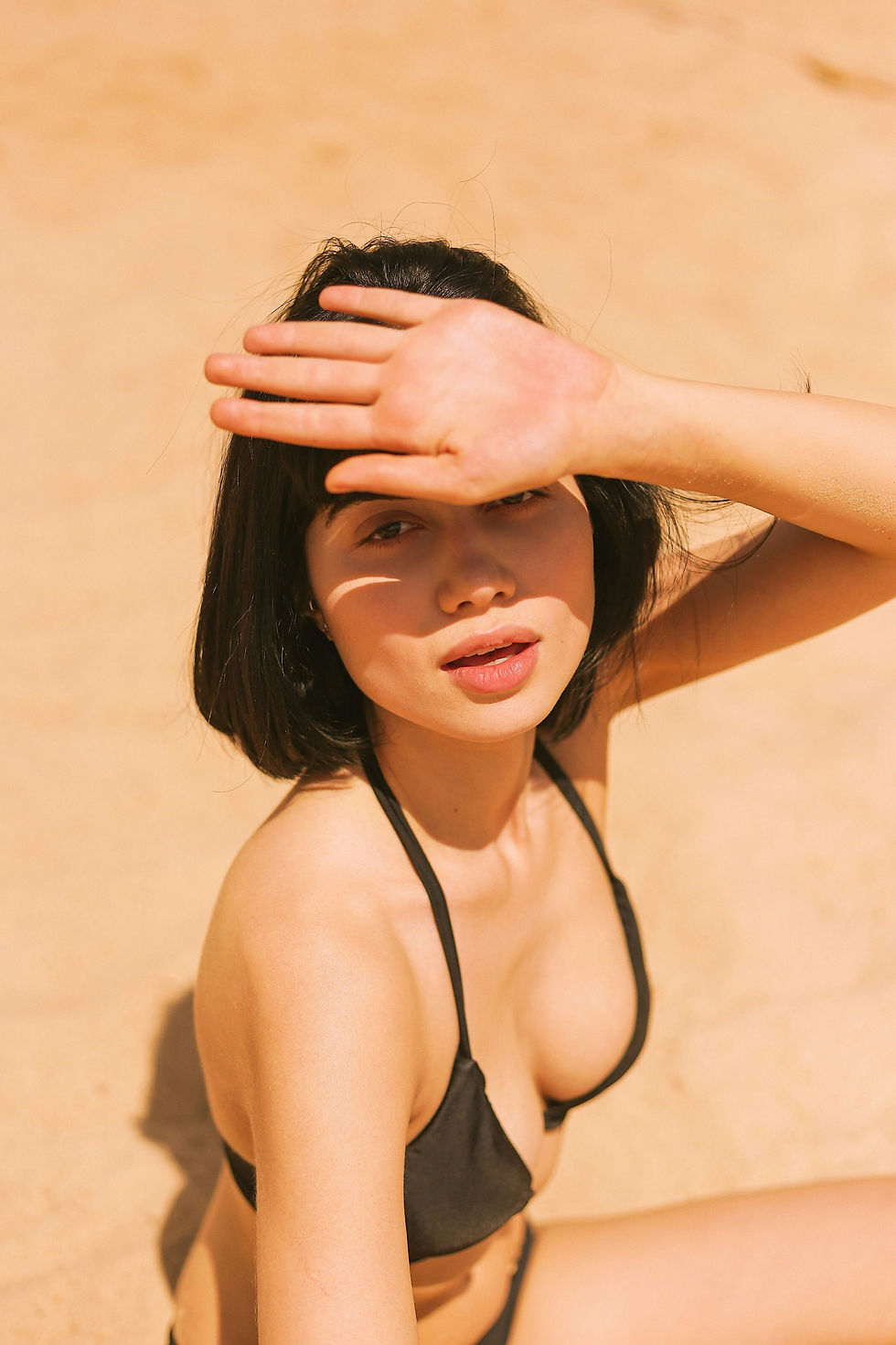 Image of a woman sitting in the sun shading here eyes so she can see