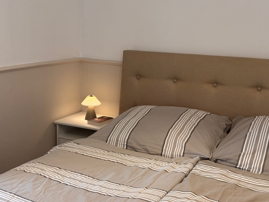 Bett und Nachttisch mit Buch und Licht