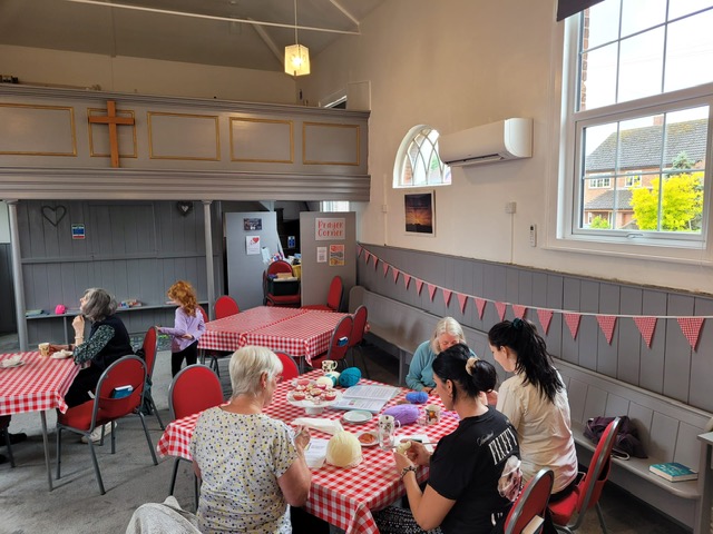 Group of people in chapel building sat at tables.