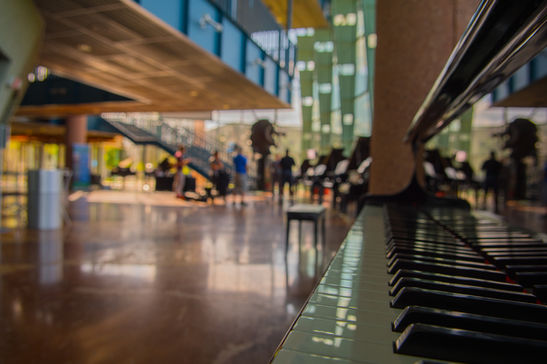 Piano keyboard in focus, with distant musicians in the Performing Arts Center at Texas A&M University-Corpus Christi.
