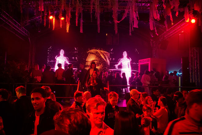 Crowd at audiovisual live performance with red lighting and digital human projections at Trädgården Stockholm, 2025