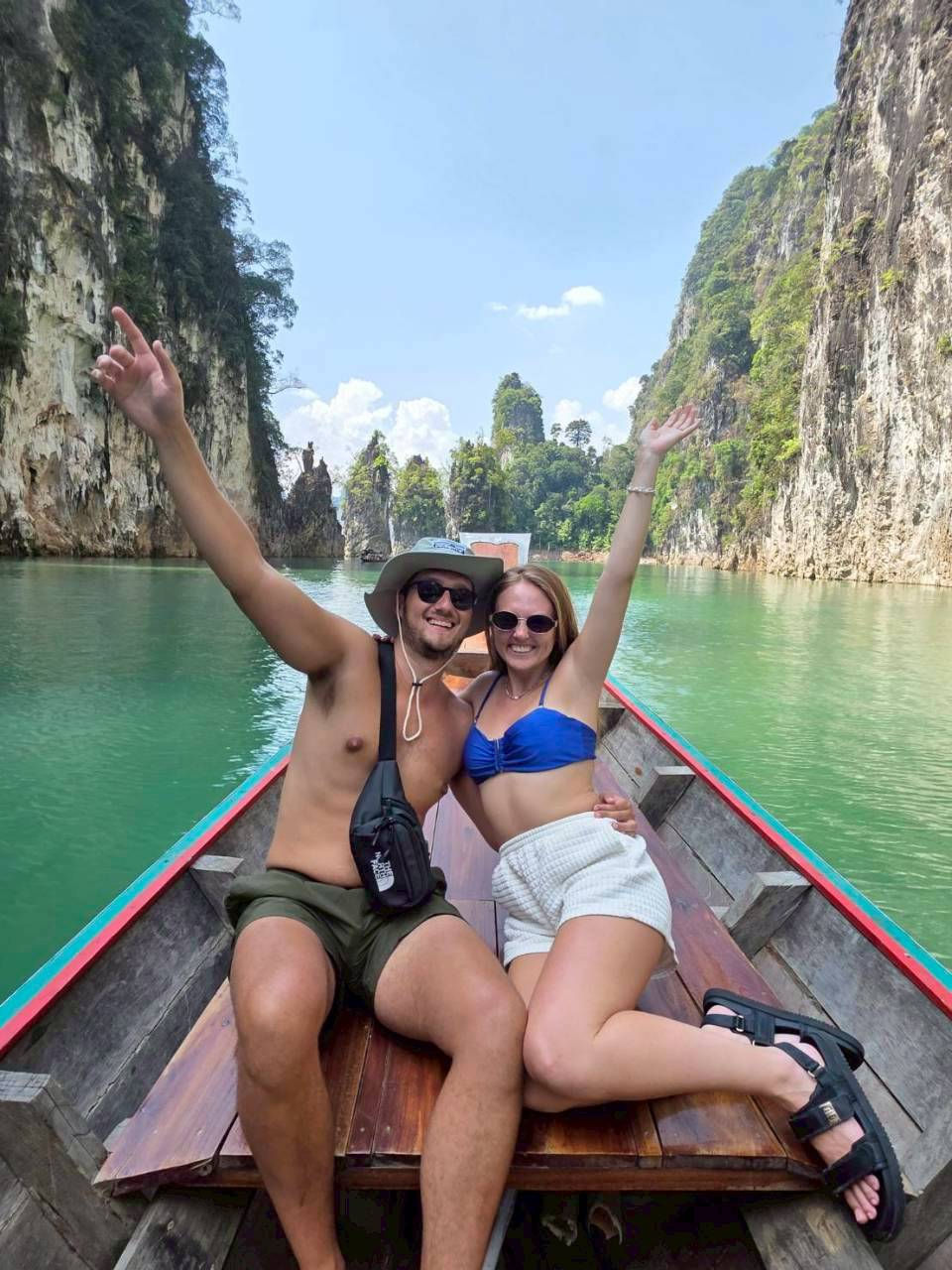 Guests posing at a longtail boat bow beneath limestone peaks.
