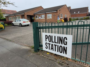 A picture of a "polling station" sign on a green gate