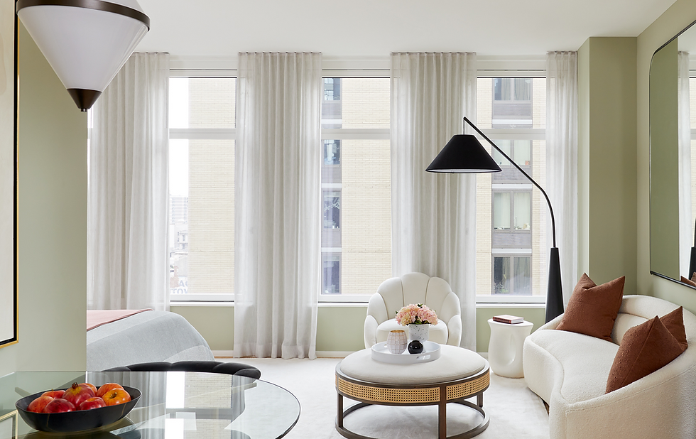 Financial District model unit living room with sheer curtains, sage green walls, and cream upholstered furnishings.