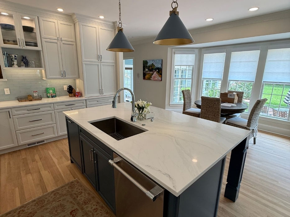 Modern kitchen with white island, dark cabinets, and pendant lights