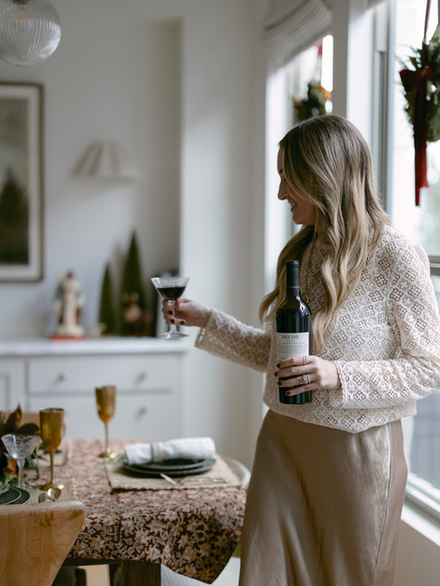 Audrey Scheck holding a glass of red wine at table decorated for the holidays