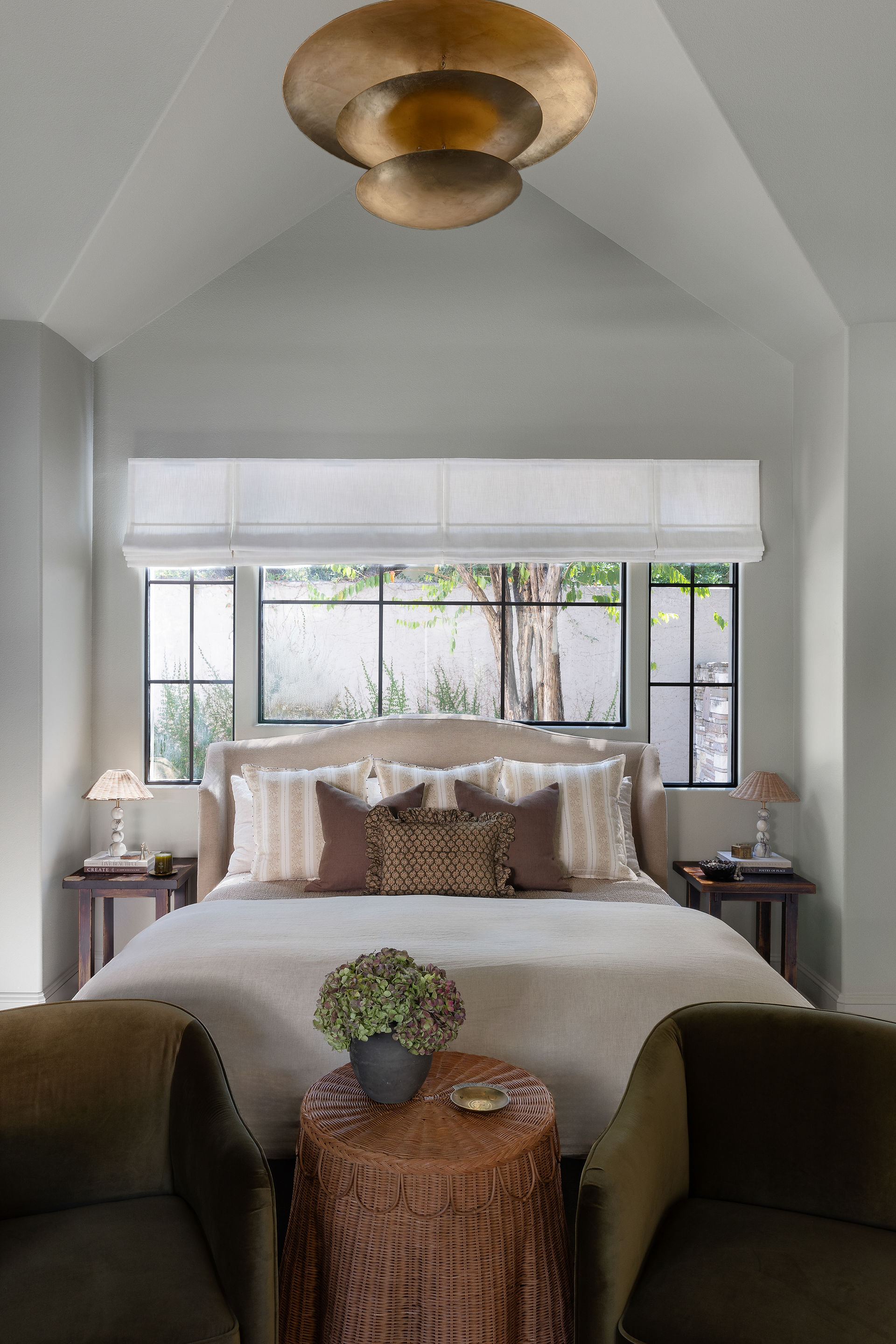 neutral light filled primary bedroom with brass light fixture