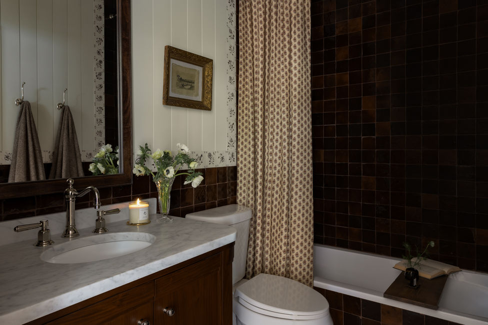 Garden Home bathroom remodel with walnut vanity, marble countertop, polished chrome fixtures, and delft tile accents.