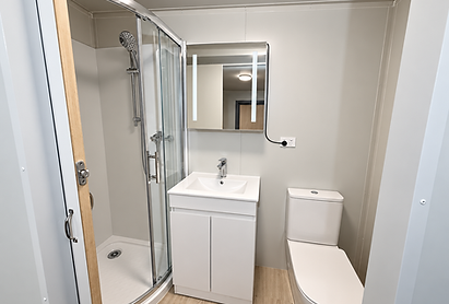 Modern ensuite bathroom in a Moving Spaces XLE portable cabin, featuring a glass shower, vanity basin, toilet and wood-effect flooring.