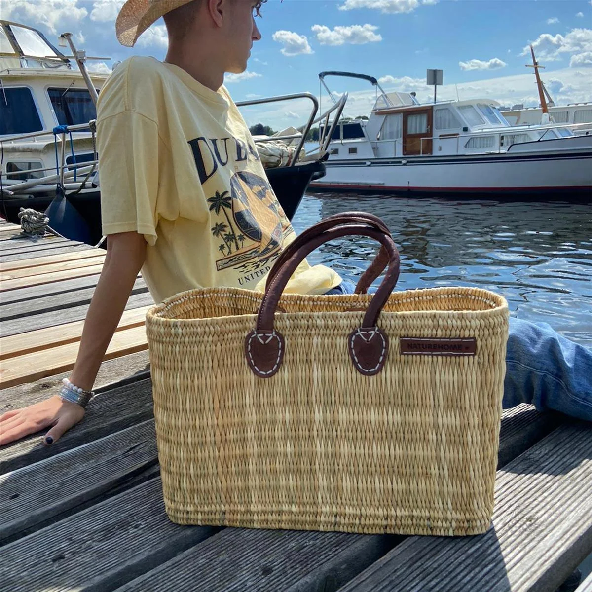 Schilfrohrtasche aus Naturmaterialien am Hafensteg, geeignet für Einkäufe, Ausflüge oder Picknicks