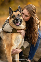 Young woman with german shepherd dog hugging and kissing on fall trail smiling joyfully