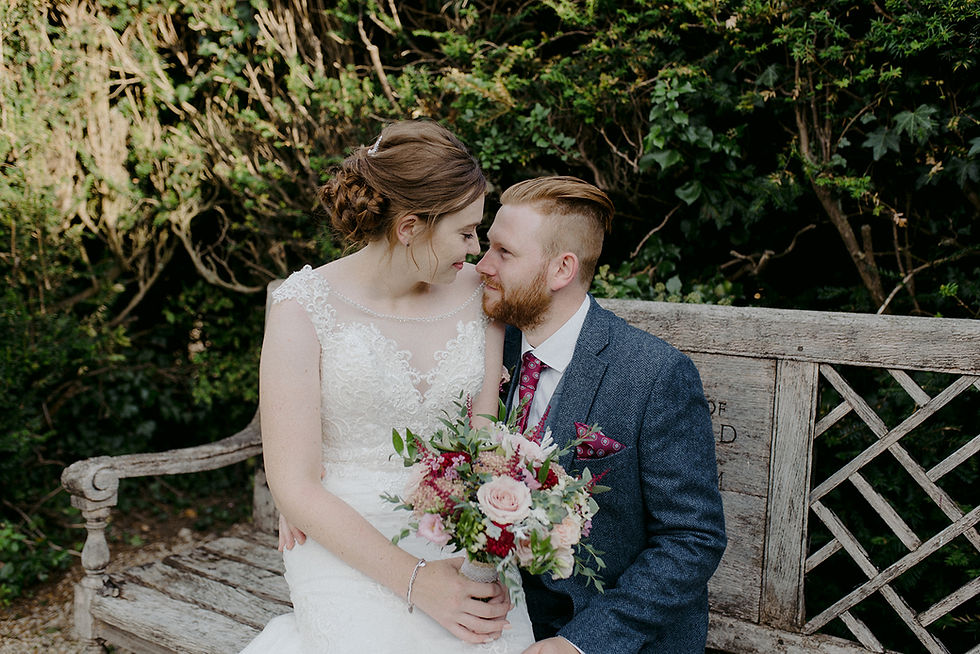 bride and groom sitting on park bench