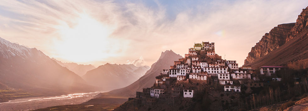Scenic view of Key Monastery in Spiti Valley at sunset, surrounded by dramatic Himalayan mountains and glowing sky.