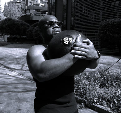 Addo the Coach doing a 40 kg front carry with medicine ball tight to his chest.