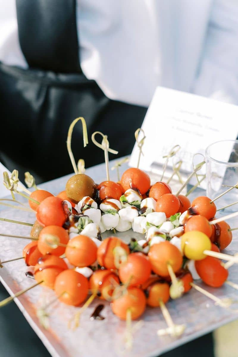 A vibrant caprese skewer platter featuring cherry tomatoes, mozzarella, and basil, drizzled with bal