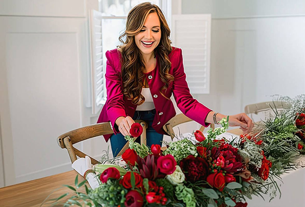 A smiling florist from The Joyful Florist perfects a vibrant red and green wedding centerpiece, sett