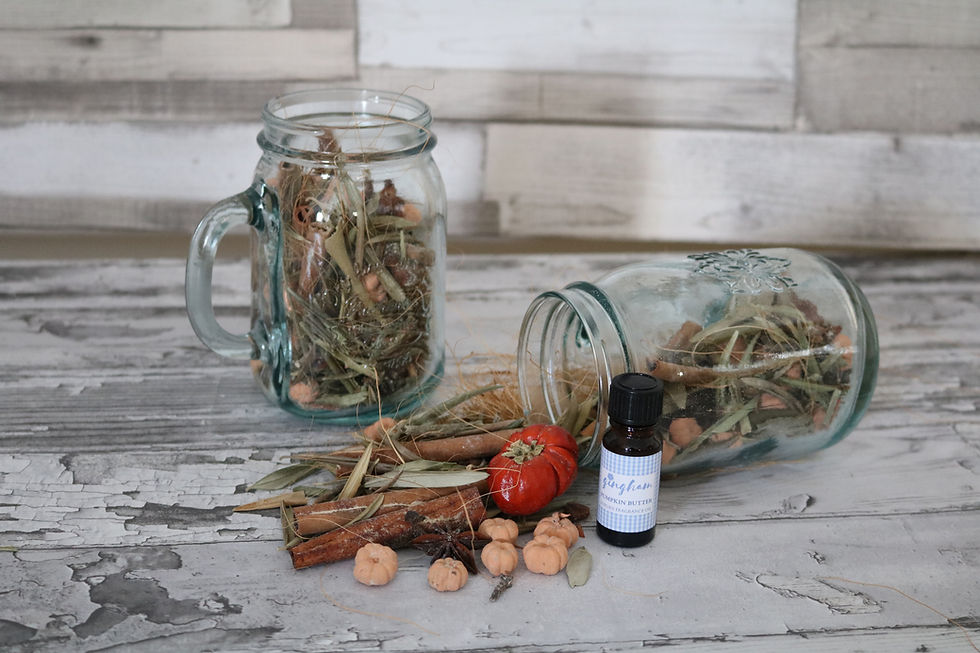 Glass jars with dried leaves, small pumpkins, and cinnamon lay on a wooden surface. A bottle labeled "Pumpkin Butter" is nearby. Rustic feel.