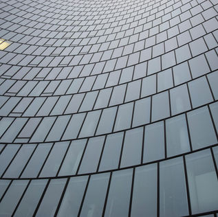 Einzelnes beleuchtetes Fenster in einer großen Glasfassade als Symbol für begrenzte Sichtbarkeit und frühe Marktvalidierung in Pilotprojekten.