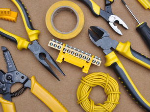 Tools with yellow accents on brown surface, including pliers, wire cutter, screwdriver, and coiled wire. Text includes "COPPER ONLY".