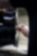 A hand polishes a glossy black car wheel with a cloth, focusing on a lug nut.