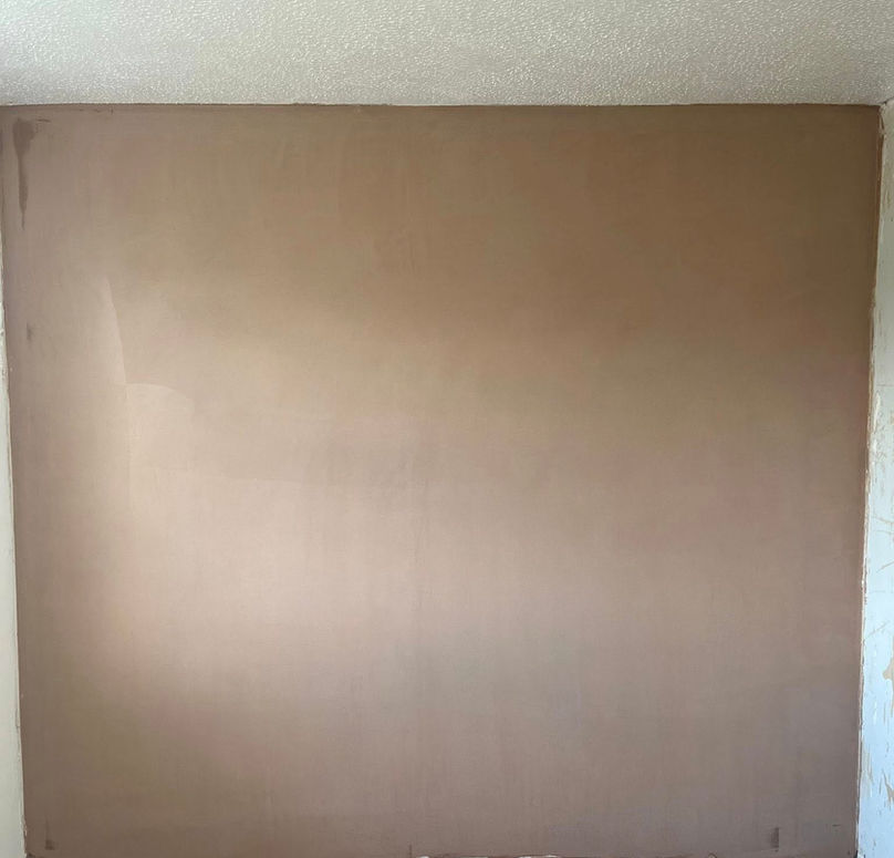 Freshly plastered wall in an empty room with a textured white ceiling