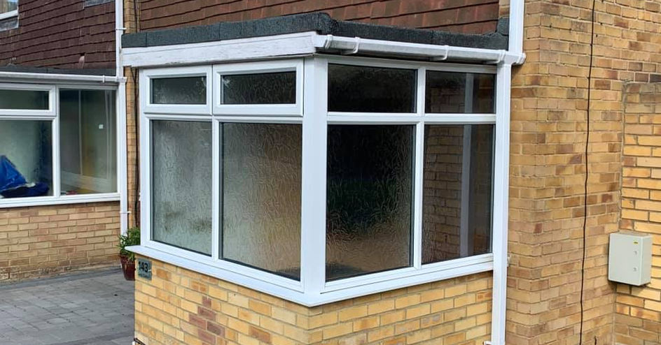 Modern white uPVC porch extension with glass windows on a yellow brick base