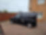 Black van parked on a brick driveway beside a house