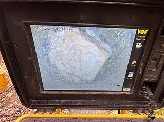 Monitor displaying an underwater camera feed showing a large rock or object submerged in murky water