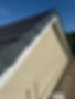 A beige stucco gable wall is topped by a sloped, dark gray tiled roof