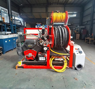 Industrial machinery with red framework and multiple coiled hoses in yellow and black inside a spacious workshop