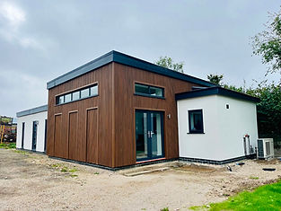 Modern flat-roofed building with wood and white exterior, featuring large windows