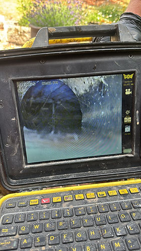 A screen displays a grainy image of the inside of a pipe