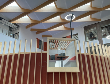 Modern interior with wooden slats and geometric ceilings, featuring a rectangular light fixture.