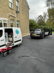 Grey Tesla Model Y parked beside mobile valeting van