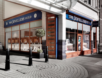 The image shows the exterior of a jewelry store with a blue sign reading