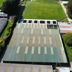 Aerial view of a large green-roofed building surrounded by grass and trees