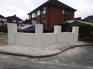 Newly rendered low white brick wall standing in front of a residential house and driveway
