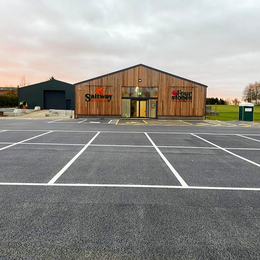 Freshly marked white parking bays on a new tarmac car park outside a modern timber building