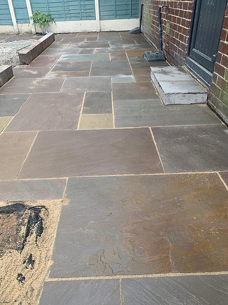A patio featuring a textured stone floor and a rustic brick wall, creating a cozy outdoor space