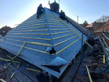 Roofing contractors fitting battens to pitched roof