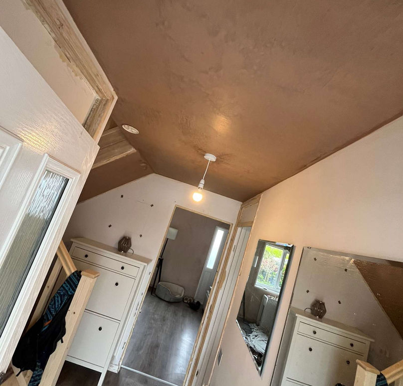 A hallway with brown walls and ceiling, white accents, mirrored decor, and wooden flooring.