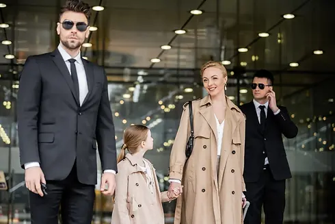 Executive bodyguard escorting a family outside a luxury hotel building