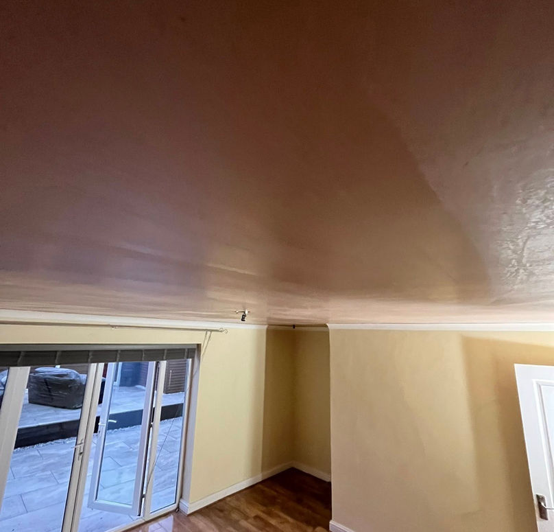 Room with cream walls and polished wooden floor, featuring an open glass door leading to a paved outdoor area