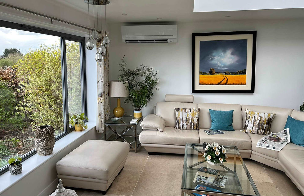 Modern white air conditioning unit installed in a bright living room above a cream leather sofa